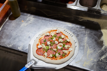 Getting ready to place tasty Italian pizza in the oven. Chef in the restaurant kitchen
