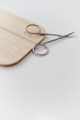 Manicure scissors resting on a wooden board, an artistic composition capturing the essence of precision and grooming in the world of nail care. Stylish simplicity in a beauty setting.