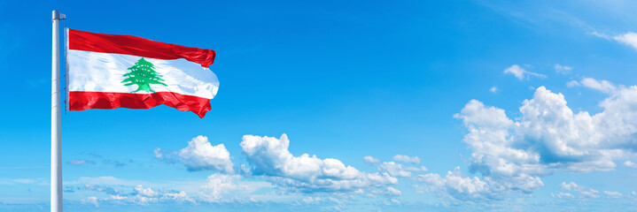 Obraz premium Lebanon flag waving on a blue sky in beautiful clouds - Horizontal banner