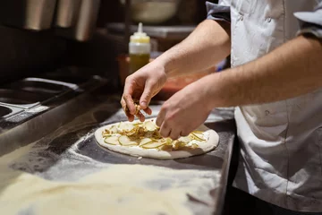 Gordijnen Pizza making process. Male chef hands making authentic pizza in the pizzeria kitchen. © arthurhidden