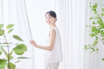 明るい窓辺で深呼吸する女性