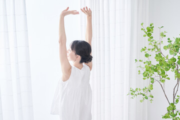 明るい窓辺で深呼吸する女性