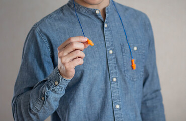 Man holds bright earplugs. Closeup.