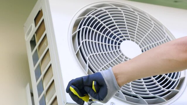 Locksmith forcefully tightens the iron bolts on the mounting of the outdoor unit air conditioner with pliers. Installation outdoor air conditioner unit by professional master using locksmith tools