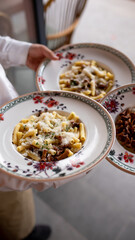 three plates of pasta in the hands of a waiter