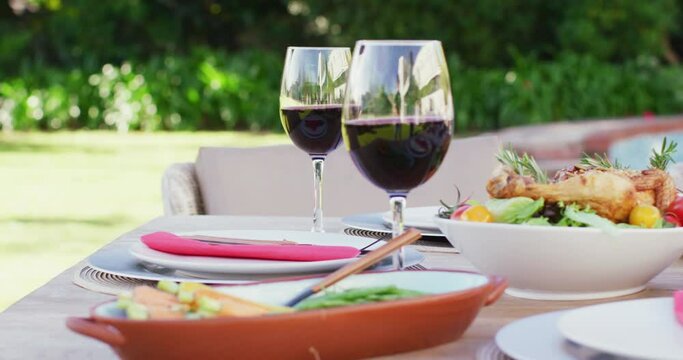 Close up of glasses of red wine and food on table in garden