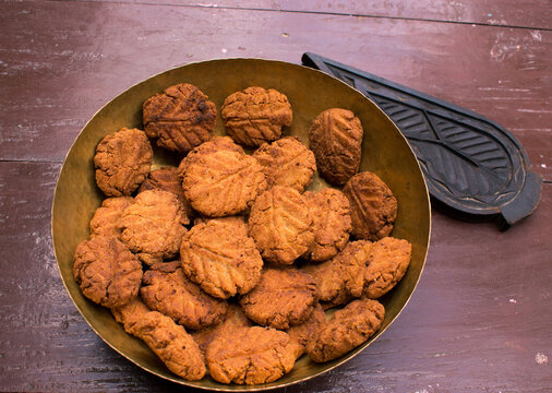 Thekua , an Indian sweet dish or a snacks in a brass plate with mold in wooden table. It is popular in bihar and jharkhand .Prashad in chhath maha parv or puja or festival. selective focus.