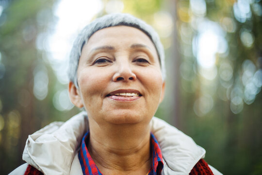 Portrait of a smiling elderly Asian woman with short gray hair in the park.