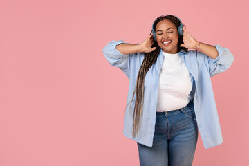 African American Oversized Lady Wearing Earphones Listening Music, Pink Background