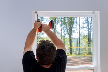 This is professional technician installing blinds on windows of newly constructed home by screwing...