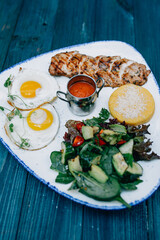 fried eggs with meat and salad