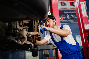Asian auto mechanic in car garage. Vehicle service personnel are inspecting cars in mechanic factory with confidence in car engine repairs. Asian mechanic with equipment to fix cars in the service.
