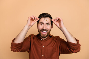 Portrait of excited crazy positive man arms touch hold glasses toothy smile isolated on beige color background
