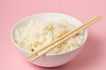 A plate of boiled rice and chopsticks on a pink background. traditional asian food