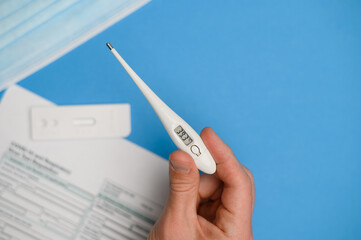 In the male hand is a thermometer with a high temperature (Celsius).Test kit for viral disease COVID-19. 