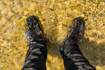 A person with shoes standing in a stream on a hot day. - 535323067