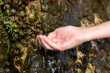 To collect fresh water from a natural spring, springs, mountain waterfall in your hand