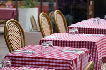 Tables on a restaurant terrace with a typical red checkered tablecloth