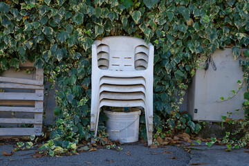 a white plastic chairs thrown out by people on the street near the forest. Pollution of the...