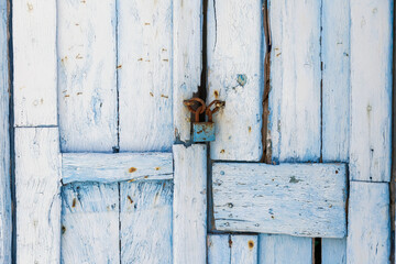 Wooden closed light blue door with rusty padlock background, texture. Greek island construction.