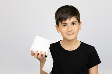 Photo of adorable young happy boy looking at camera. Active boy playing with toilet paper in white...