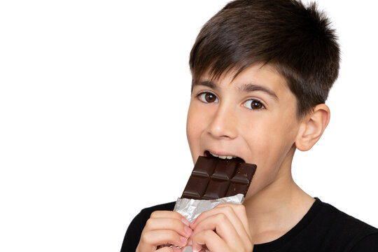 Photo Of Adorable Young Happy Boy Looking At Camera.Isolated On The White Background. Little Kid Bites A Brown Chocolate Bar.