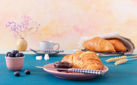 Tasty Breakfast With Croissants, Fresh Blueberries, Jam And Cup Of Coffee. Blue Wooden Table, Low Angle Of View, No People.