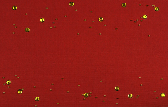 Golden beeds and sequins on red paper for Christmas or Valentine Day