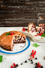 pieces of sliced berry fruit cake with black and red currants on a gray concrete background 1
