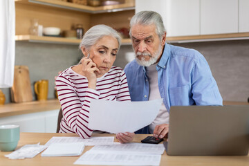 Upset Elderly Couple Checking Financial Documents While Calculating Family Budget At Home
