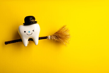 dental concept. tooth figurine in halloween costume and dental tools. pumpkins and a broom. on a...
