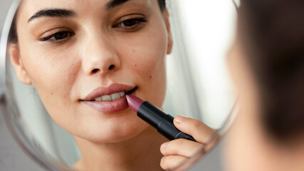 Closeup image of a woman applying lipstick