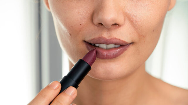 Closeup image of a woman applying lipstick
