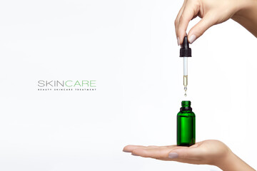 Cosmetology and skincare concept. Beautiful female hands holds pipette and glass dropper bottle...
