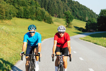 Professional road racing cyclist couple in sports jerseys, wearing bike helmets and sunglasses...