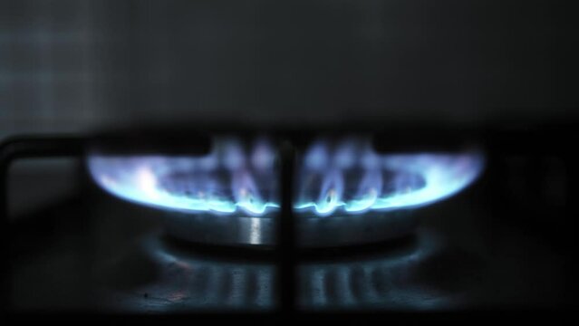 Gas stove being turned on by a lit burner close up. Natural gas concept.