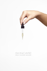 Cosmetology and skincare concept. Close up of beautiful female hand holding the pipette of a dropper. Vertical format isolated on white background with copy space