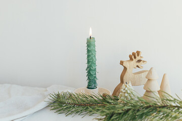 Merry Christmas and Happy Holidays! Stylish christmas candle as fir tree, wooden trees and deer,...