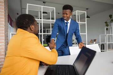handshake of two successful african men in suits in the office	