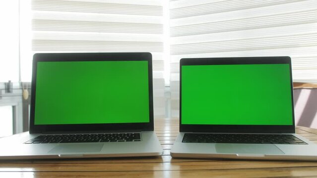 Workplace with modern wireless laptops of software engineer. Close up of green chroma key screens.