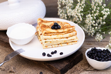 pancakes are placed in a triangle with blueberries on a white plate laid on a wooden background