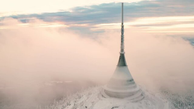 Jested broadcast tower with hotel built on forestry mountain top surrounded with fog cloud. Modern building with spire as symbol of Liberec aerial view