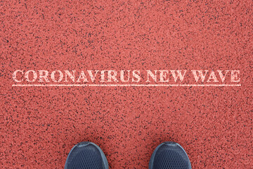 Feet stand in front of the inscription Coronavirus new wave. Pandemic concept