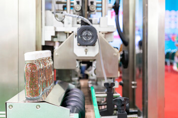 Small grain like product in clear bottle glass are placed arrange row on automatic solid filling and capped machine in manufacturing process