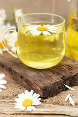 Obraz na płótnie Canvas chamomile tea is a therapeutic healthy drink cup on a wooden background Concept of medicinal herbs. phytotherapy. Vertical photography