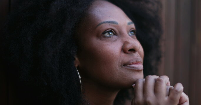 African woman feeling HOPE and GRACE. Person praying to GOD looking at sky