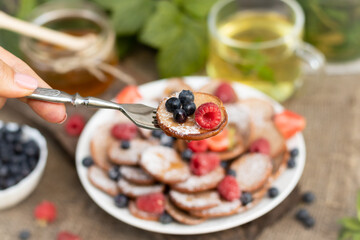 mini pancakes chocolate pancakes with blueberries and raspberries on a white plate On a wooden background