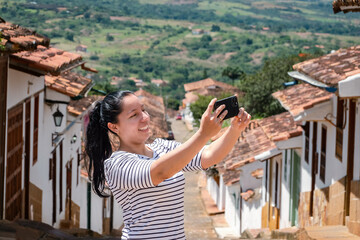 Fototapeta na wymiar Young woman doing tourism in old town of Colombia, woman making selfie in colonial town, Barichara
