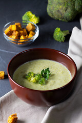 broccoli soup in a brown bowl.green Broccoli cream soup on black background with copy space. Fresh broccoli soup healthy eating. vegetable soup with crackers.