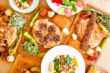 Delicious meat kebab with fresh vegetable salad served with variety of Turkish dishes and appetizers. Top view of assorted Turkish food and meze, tasty and healthy Mediterranean cuisine.